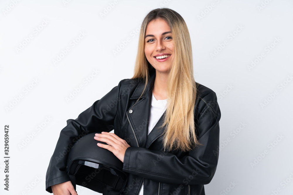 Young Uruguayan woman with a motorcycle helmet over isolated white background laughing Young Uruguayan woman with a motorcycle helmet over isolated white background laughing