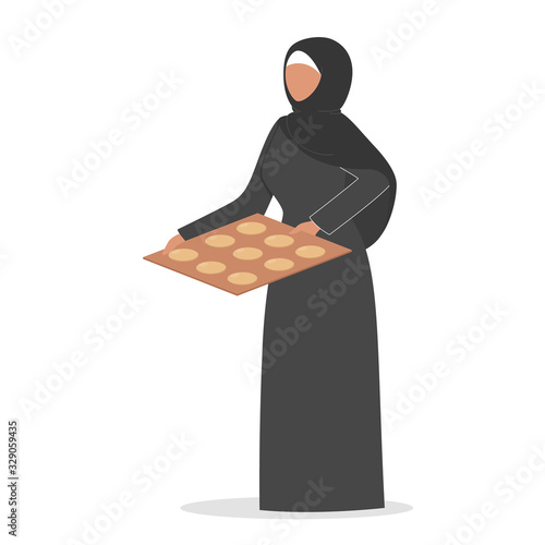 Muslim woman with baking sheet and cookie on it. Arabian woman