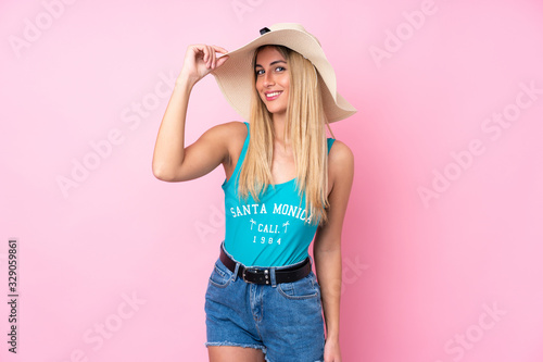 Young blonde Uruguayan woman in swimsuit in summer holidays over isolated pink background