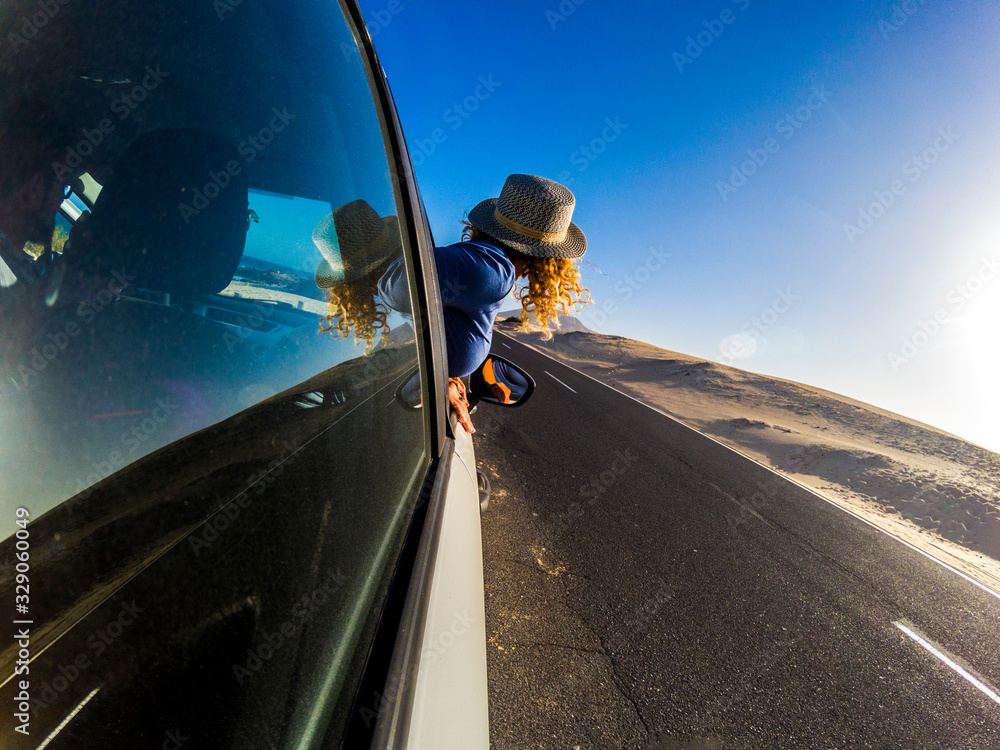 Travel and freedom with blonde girl viewed form back and long asphalt road in background - car vehicle traveler lifestyle people - outdoor transport activity  and blue sky