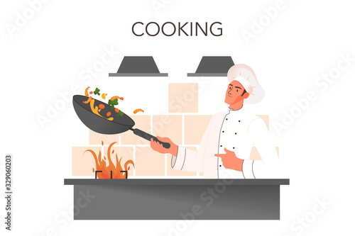 Male restaurant chef in white uniform cooking meal on the kitchen.