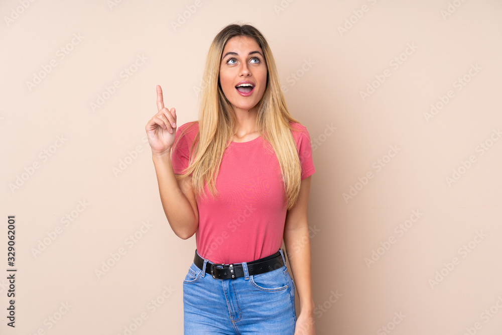 Young Uruguayan woman over isolated background pointing up and surprised Young Uruguayan woman over isolated background pointing up and surprised