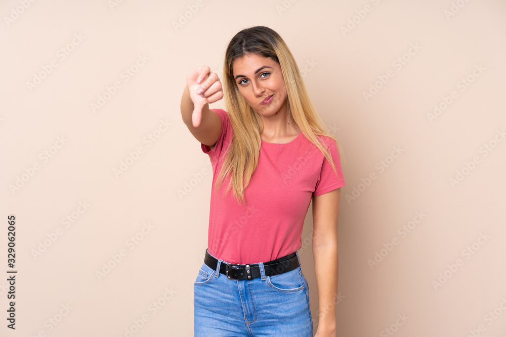 Young Uruguayan woman over isolated background showing thumb down with negative expression Young Uruguayan woman over isolated background showing thumb down with negative expression