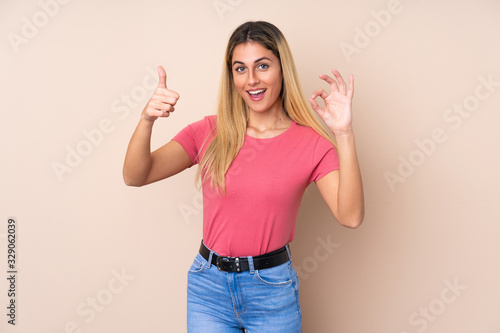 Young Uruguayan woman over isolated background showing ok sign and thumb up gesture