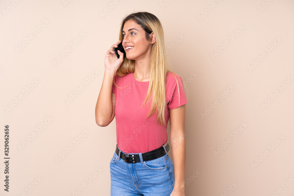 Young Uruguayan woman over isolated background keeping a conversation with the mobile phone with someone Young Uruguayan woman over isolated background keeping a conversation with the mobile phone with someone