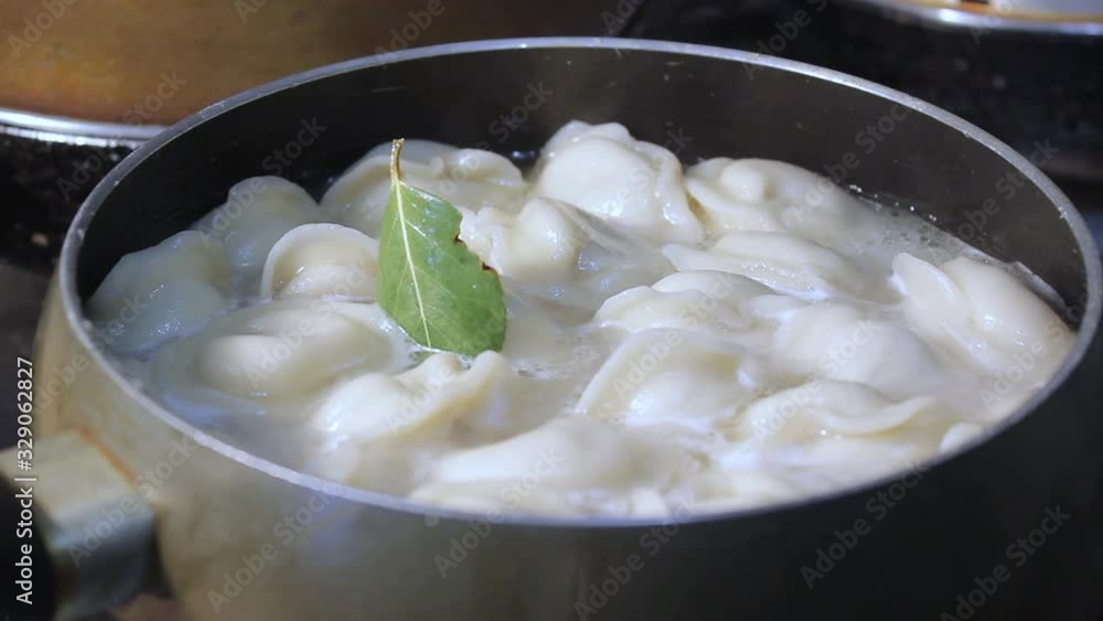 meat dumplings are cooked in boiling water in the kitchen. the chef is stirring the broth with a cooking device meat dumplings are cooked in boiling water in the kitchen. the chef is stirring the broth with a cooking device