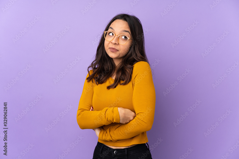 Young mixed race woman isolated on purple background making doubts gesture while lifting the shoulders Young mixed race woman isolated on purple background making doubts gesture while lifting the shoulders