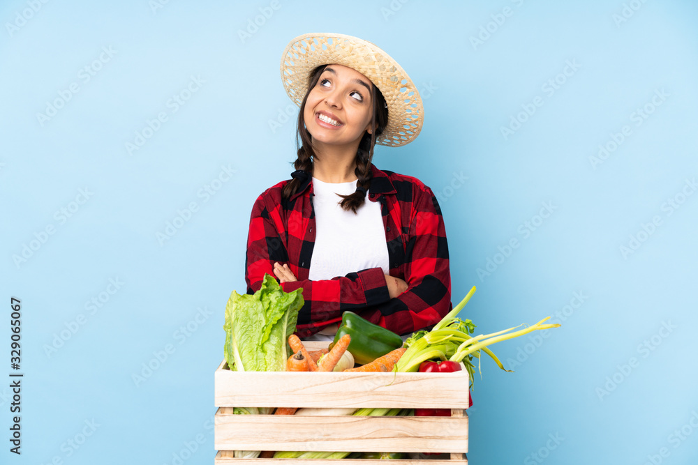 Young farmer Woman holding fresh vegetables in a wooden basket looking up while smiling