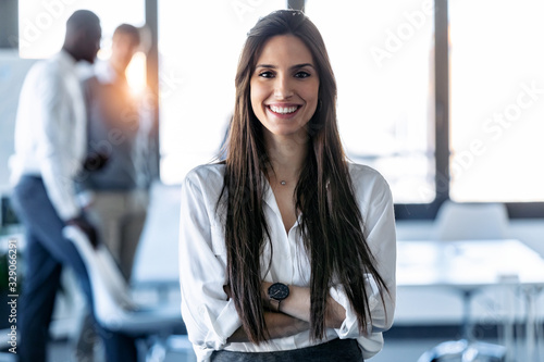 Smiling young businesswoman looking at camera while standing in the coworking space.