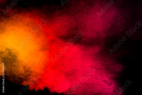 Abstract yellow orange powder explosion on black background.Freeze motion of yellow orange dust particles splash.
