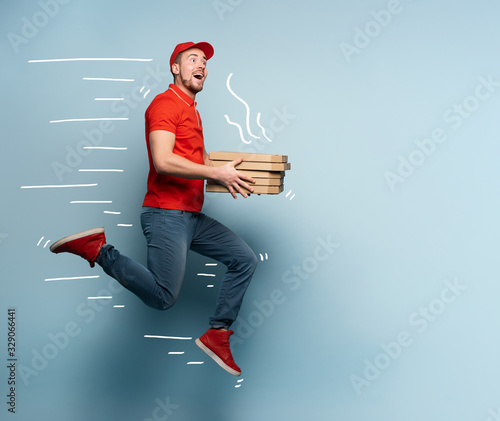 Courier runs fast to deliver quickly pizzas. Cyan background photo