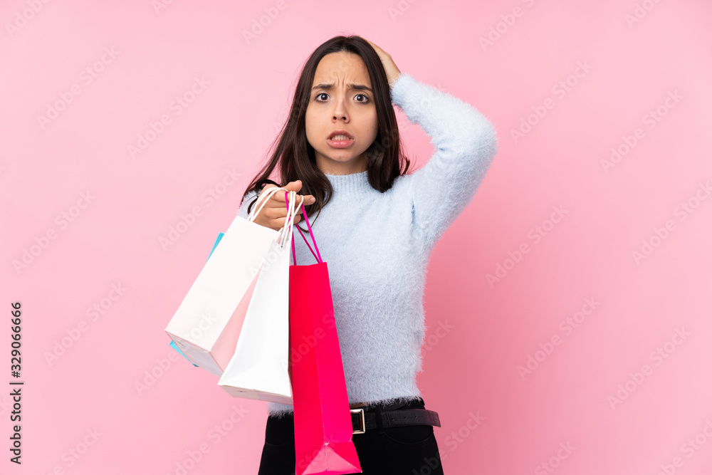 Young woman with shopping bag over isolated pink background with an expression of frustration and not understanding