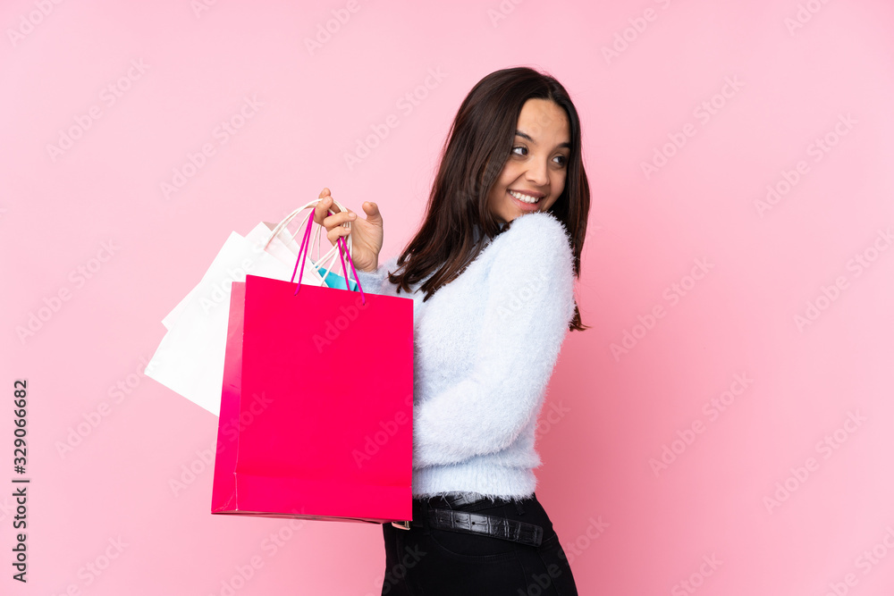 Fototapeta premium Young woman with shopping bag over isolated pink background with arms crossed and happy