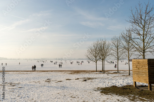 Spaziergänger laufen über das gefrorene Eis des Altmühlsees im Fränkischen Seenland. Im Winter friert der See teils zu. Nur selten ist er wie hier begehbar. Der Altmühlsee ist in Mittelfranken Bayern. photo