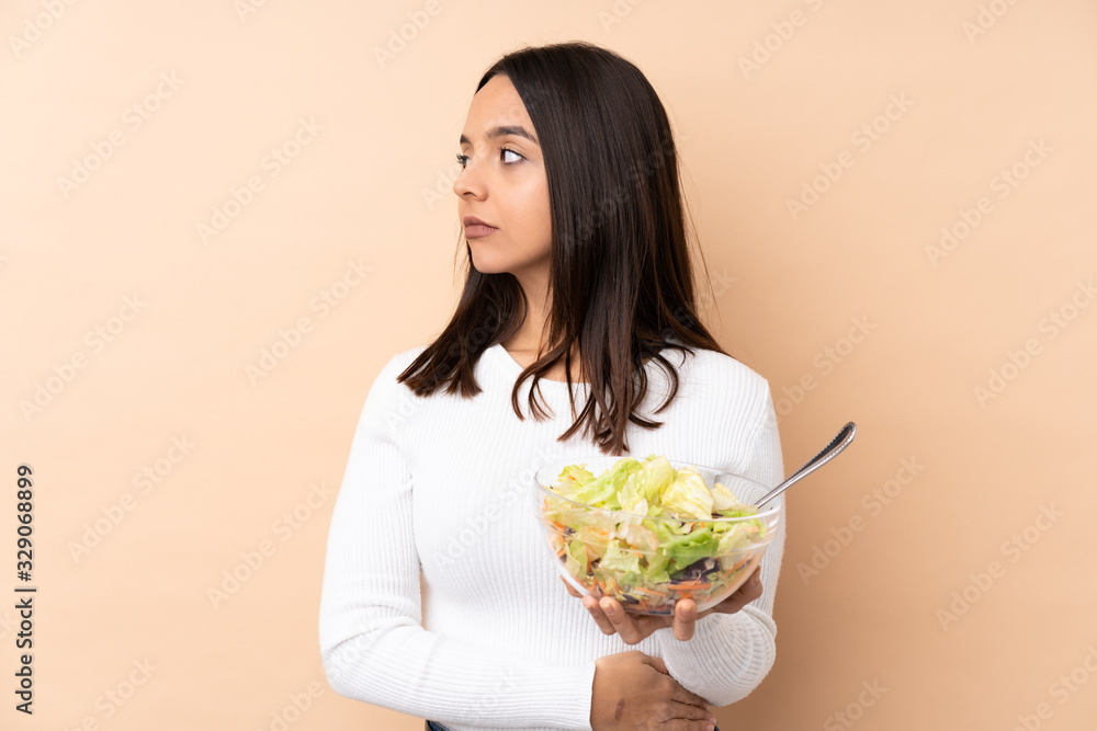 Young brunette girl holding a salad over isolated background portrait