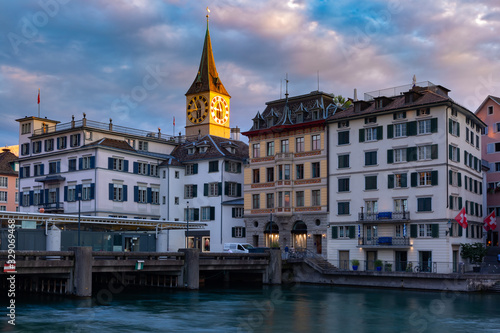 Sunny church of St Peter and medieval houses along river Limmat at sunset in Old Town of Zurich, the largest city in Switzerland © Kavalenkava