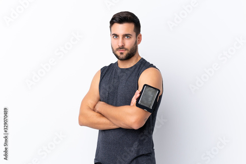 Young sport handsome man with beard over isolated white background with arms crossed © luismolinero