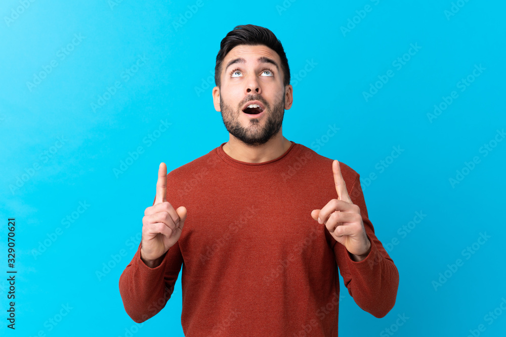 Young handsome man with beard over isolated blue background pointing with the index finger a great idea Young handsome man with beard over isolated blue background pointing with the index finger a great idea