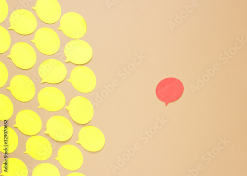 Empty yellow speech bubbles on beige background. Copy space. Abstract texture of small paper stickers. Different opinion concept