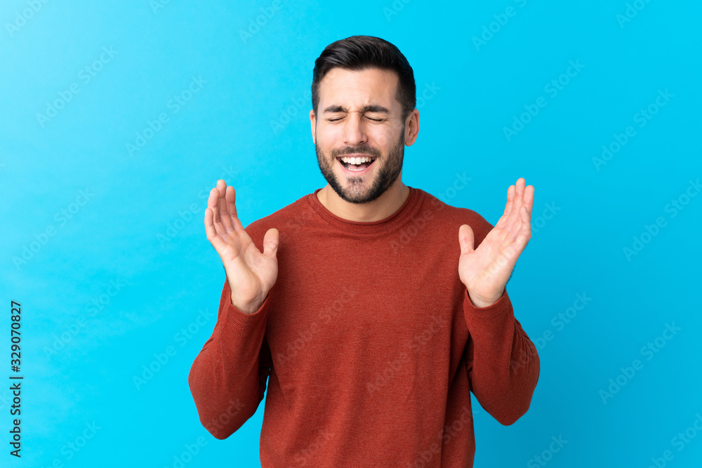 Young handsome man with beard over isolated blue background laughing Young handsome man with beard over isolated blue background laughing