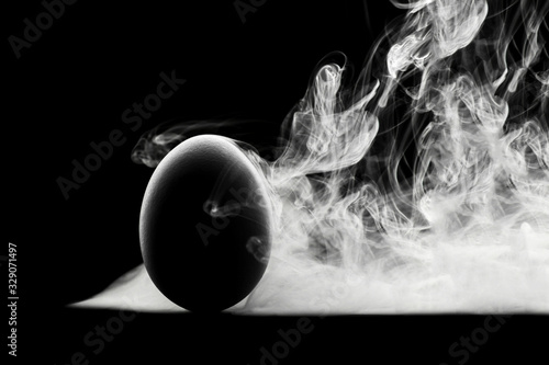 concept. The contour of the eggs on a black background and white steam or smoke. photo