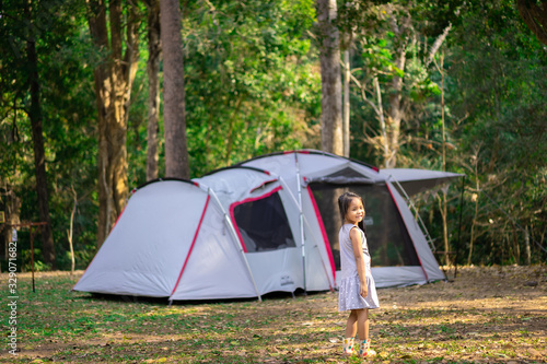 little girl standing in front of tent while going camping.The concept of outdoor activities and adventures in nature.