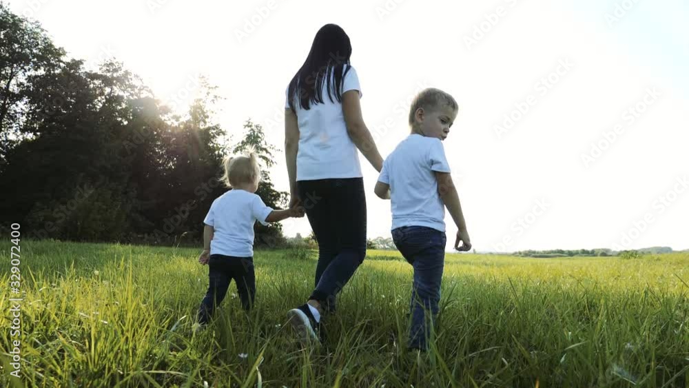 happy family teamwork mother, little brother and sister walk in the park nature holding hands slow motion video concept. mom, kids boy and girl daughter and son hold hands go lifestyle on green grass happy family teamwork mother, little brother and sister walk in the park nature holding hands slow motion video concept. mom, kids boy and girl daughter and son hold hands go lifestyle on green grass