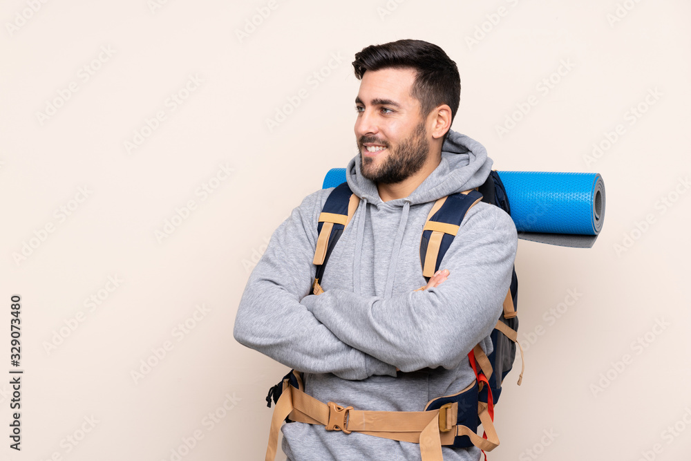Young mountaineer man with a big backpack over isolated background looking to the side Young mountaineer man with a big backpack over isolated background looking to the side