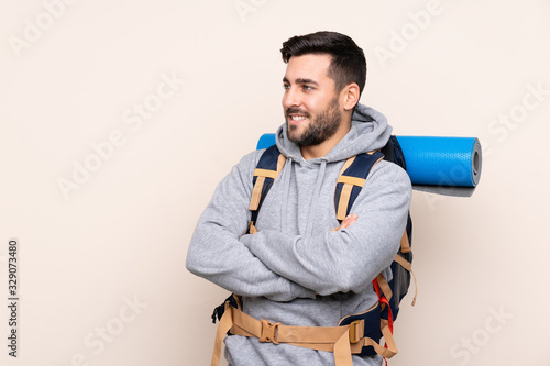 Young mountaineer man with a big backpack over isolated background looking to the side
