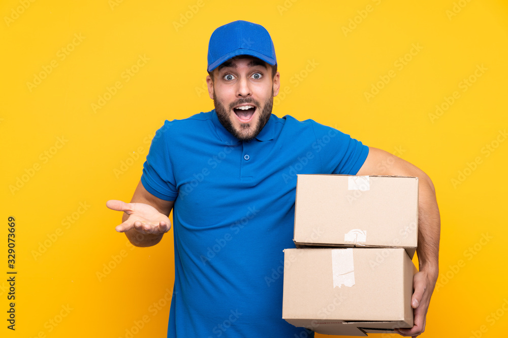 Delivery man over isolated yellow background with shocked facial expression Delivery man over isolated yellow background with shocked facial expression