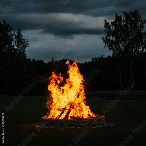 Big bonfire at night, burning trees.