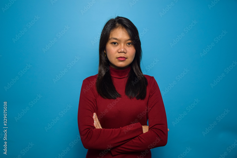 Portrait of Young beautiful asian women with blue isolated background, serious face gesture and folding hands Portrait of Young beautiful asian women with blue isolated background, serious face gesture and folding hands