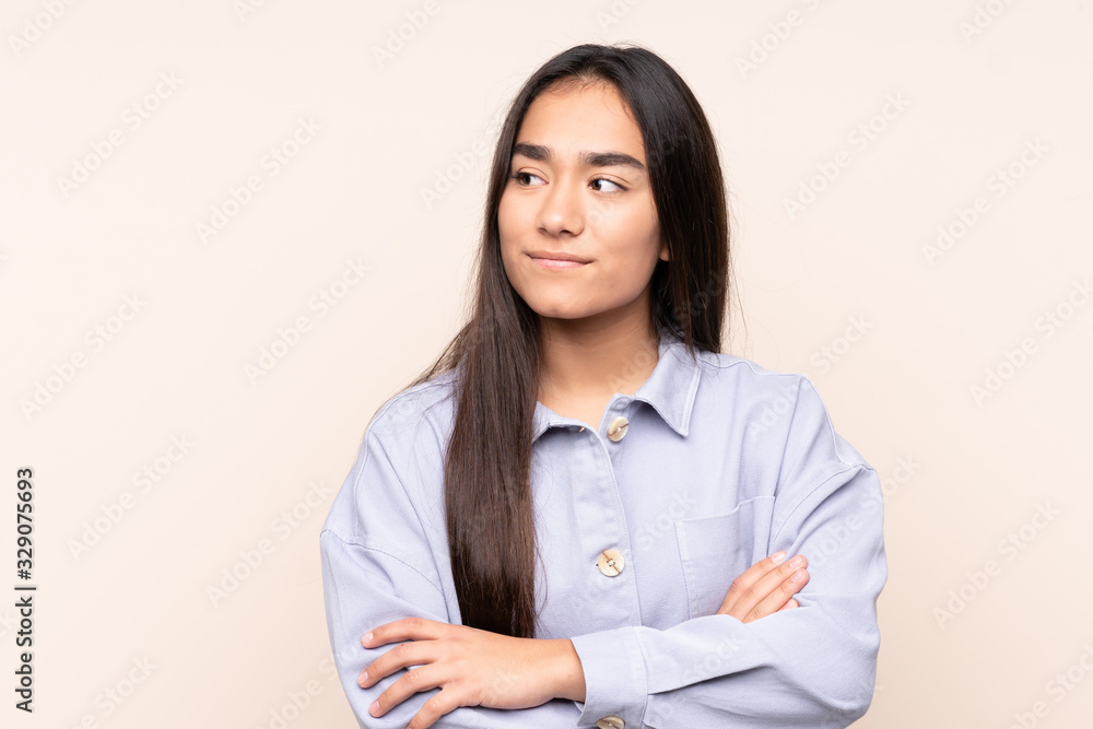 Young Indian woman isolated on beige background looking to the side Young Indian woman isolated on beige background looking to the side