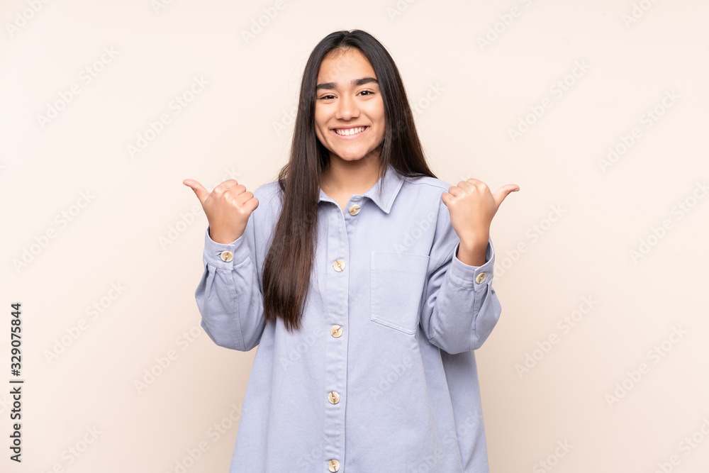 Young Indian woman isolated on beige background with thumbs up gesture and smiling Young Indian woman isolated on beige background with thumbs up gesture and smiling