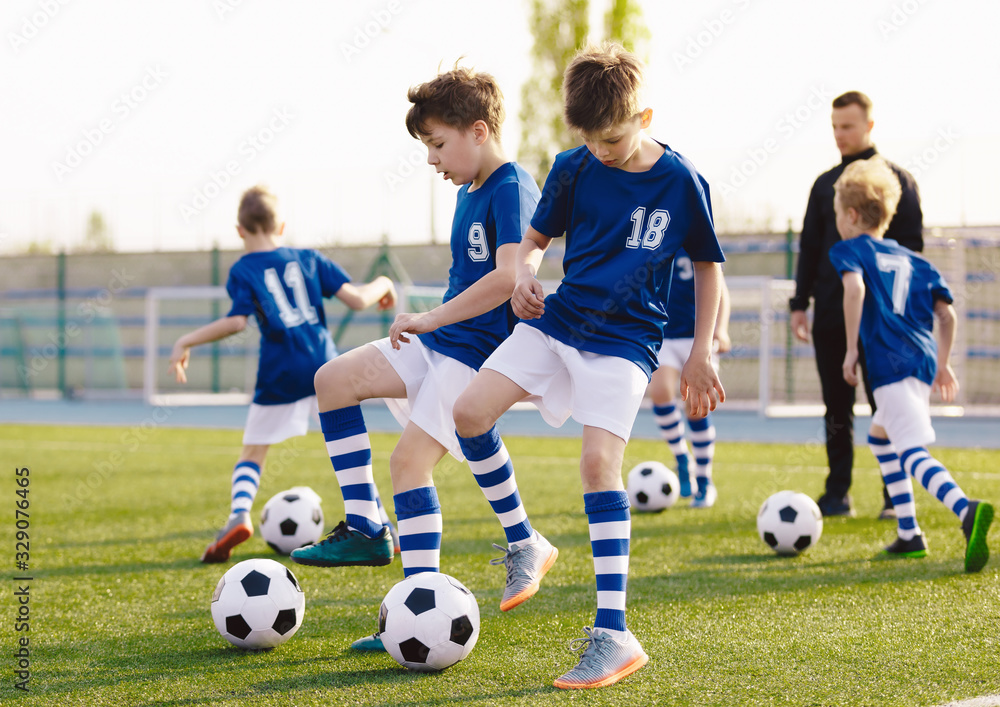 Soccer Training Exercises for Kids. Boys Training with Balls on Summer Football Grass Field. Young Sporty Kids in a Team with Coach. Practice Soccer Unit for School Children. Stadium in the Background