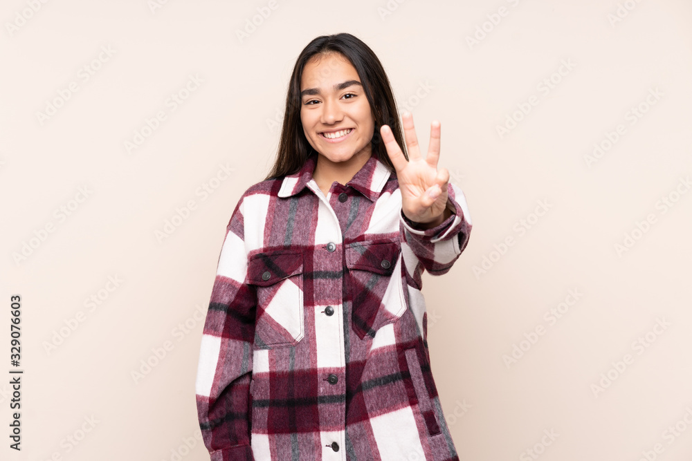 Young Indian woman isolated on beige background happy and counting three with fingers Young Indian woman isolated on beige background happy and counting three with fingers