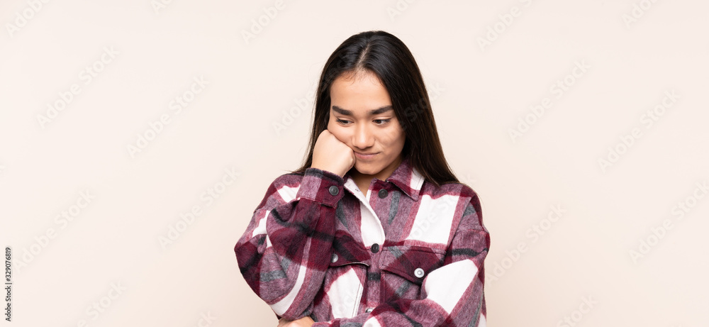 Young Indian woman isolated on beige background with tired and bored expression Young Indian woman isolated on beige background with tired and bored expression
