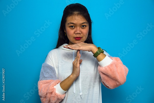 Portrait of Young beautiful asian women with blue isolated background, Doing time out gesture with hands