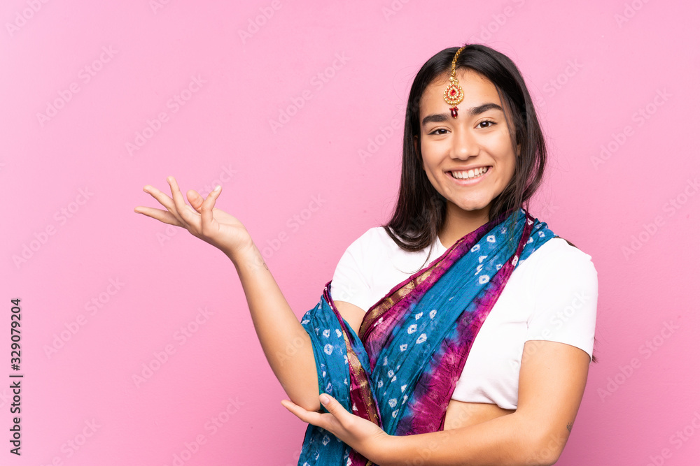 Young Indian woman with sari over isolated background extending hands to the side for inviting to come Young Indian woman with sari over isolated background extending hands to the side for inviting to come