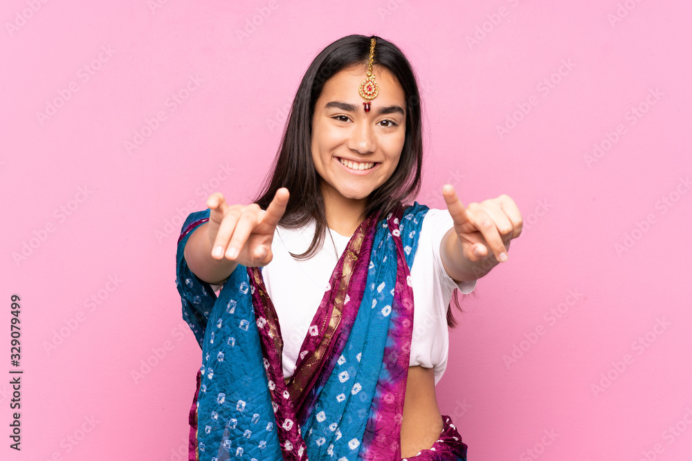 Young Indian woman with sari over isolated background points finger at you while smiling Young Indian woman with sari over isolated background points finger at you while smiling