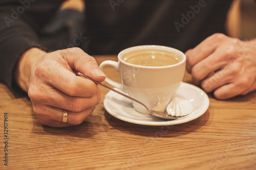 Closeup hand of male holding a coffee cup in the cafe add the filter retro color tone.  How to lifestyle of adult businessman in the weekend activity relaxing with the coffee drinking concept.