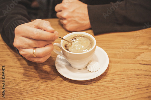 Closeup hand of male holding a coffee cup in the cafe add the filter retro color tone., How to lifestyle of adult businessman in the weekend activity relaxing with the coffee drinking concept.