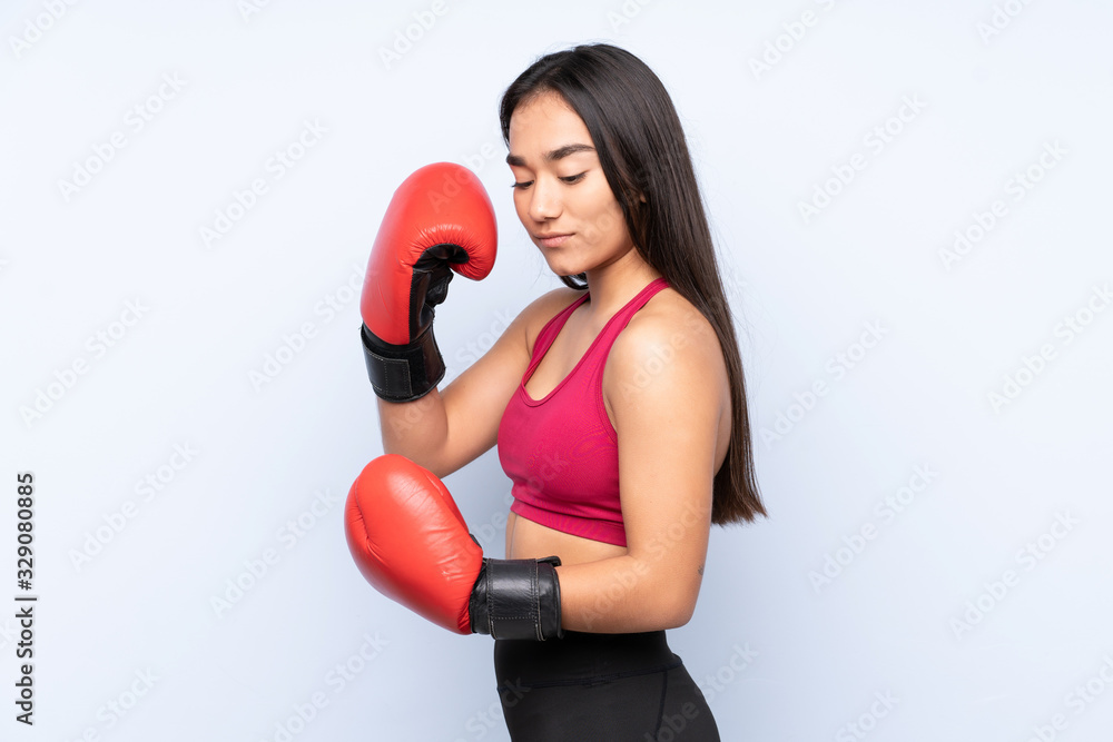 Young Indian sport woman isolated on blue background with boxing gloves Young Indian sport woman isolated on blue background with boxing gloves
