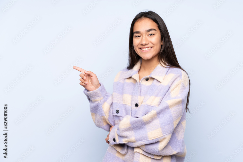 Young Indian woman isolated on blue background pointing finger to the side Young Indian woman isolated on blue background pointing finger to the side