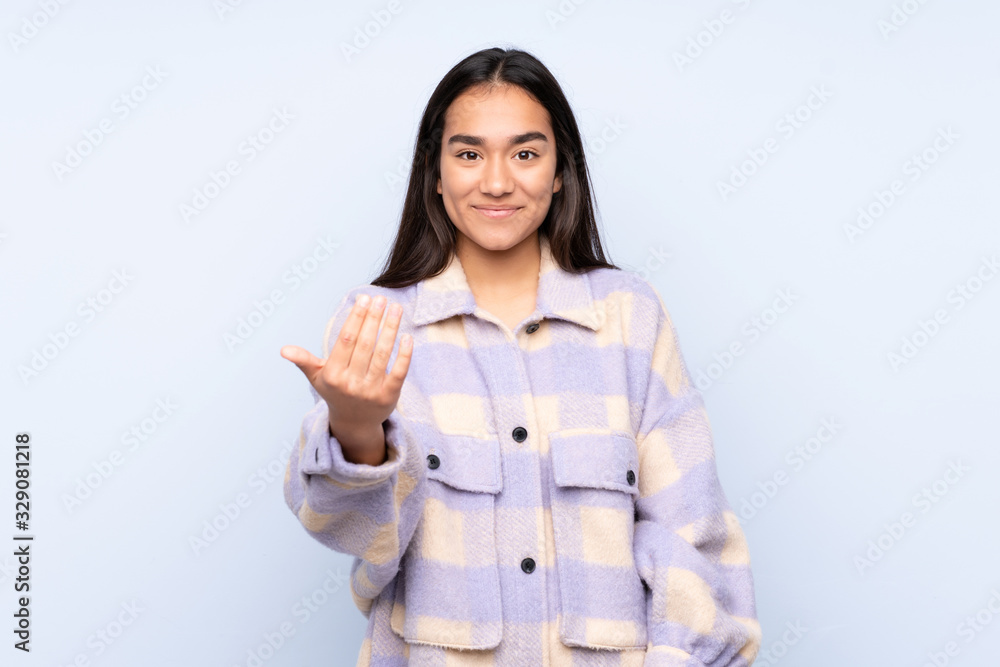 Young Indian woman isolated on blue background inviting to come with hand. Happy that you came Young Indian woman isolated on blue background inviting to come with hand. Happy that you came