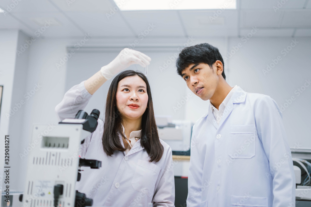 Two young medical scientist looking at test tube in medical laboratory Two young medical scientist looking at test tube in medical laboratory