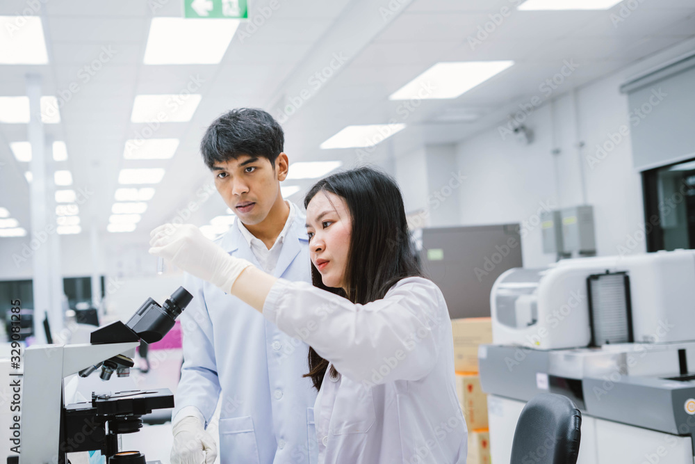 Obraz premium Two young medical scientist looking at test tube in medical laboratory , select focus on young female scientist
