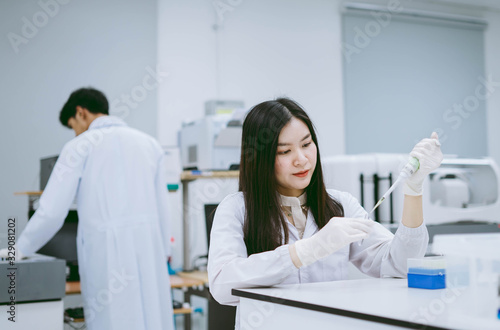 Young medical  scientist working in medical laboratory   young female scientist  using auto pipette to transfer sample