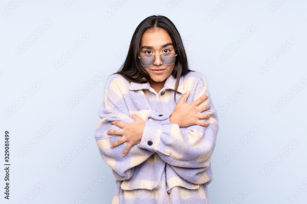 Young Indian woman isolated on blue background freezing Young Indian woman isolated on blue background freezing