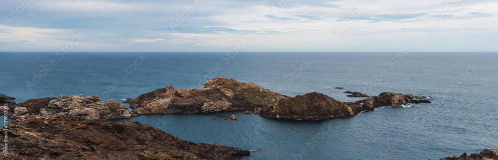 Big rocks in the Mediterranean sea with the horizon of the blue sea and a cloudy day